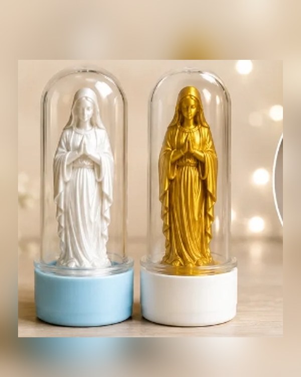 Duas imagens de Nossa Senhora, uma branca e uma dourada, dentro de tubetes transparentes com base colorida.